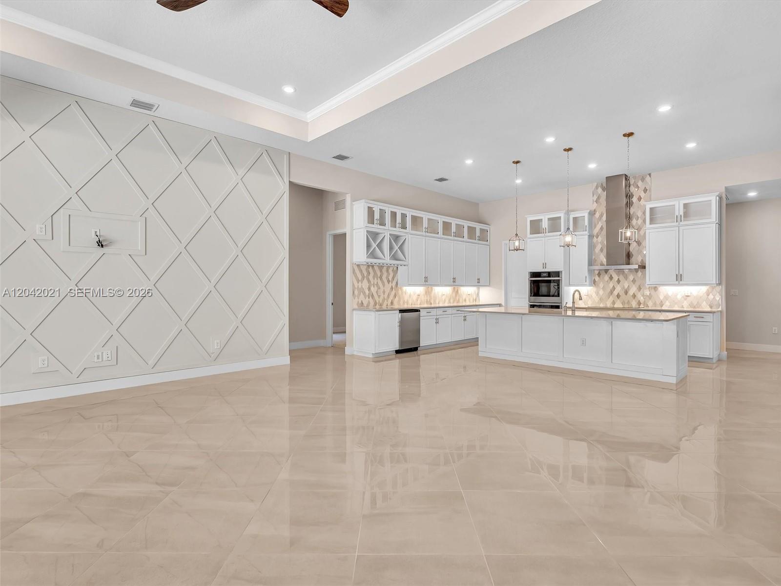 A spacious kitchen and living area feature white cabinetry, a large island, and tiled floors — 7680 Cavern Ln, Parkland FL 33067, PARKLAND, FL