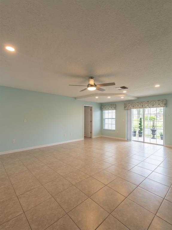 A spacious living area features light blue walls, tile flooring, a ceiling fan, and sliding doors — 6648 TIMBERCOVE LANE UNIT 6648, NEW PORT RICHEY, FL