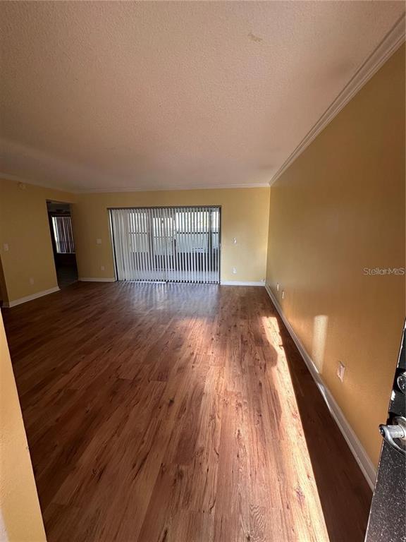 An empty room features yellow walls, wood-look flooring, and sliding glass doors with vertical blinds — 4725 PURITAN CIRCLE UNIT 603, TAMPA, FL