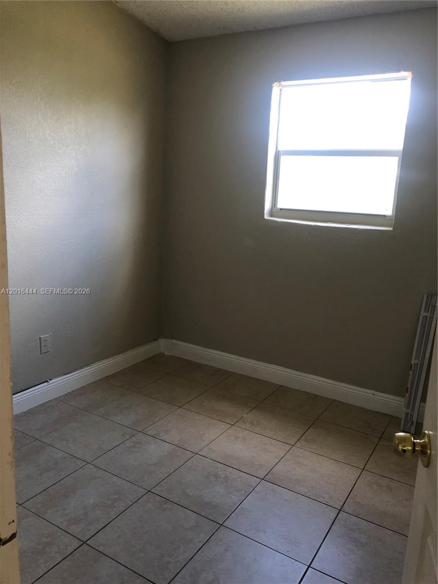 A small room features beige walls, light-colored tile flooring, and a single window — 640 SW 7th St, Homestead FL 33030, HOMESTEAD, FL