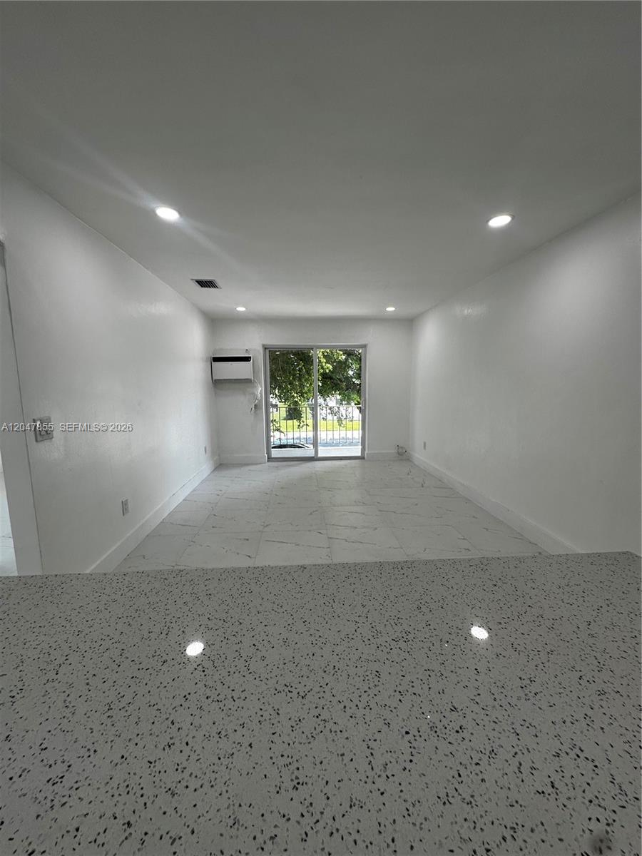 A view from a kitchen counter looking into a living room with white tile floors — 1945 NW 29th St # A5, Miami FL 33142, MIAMI, FL