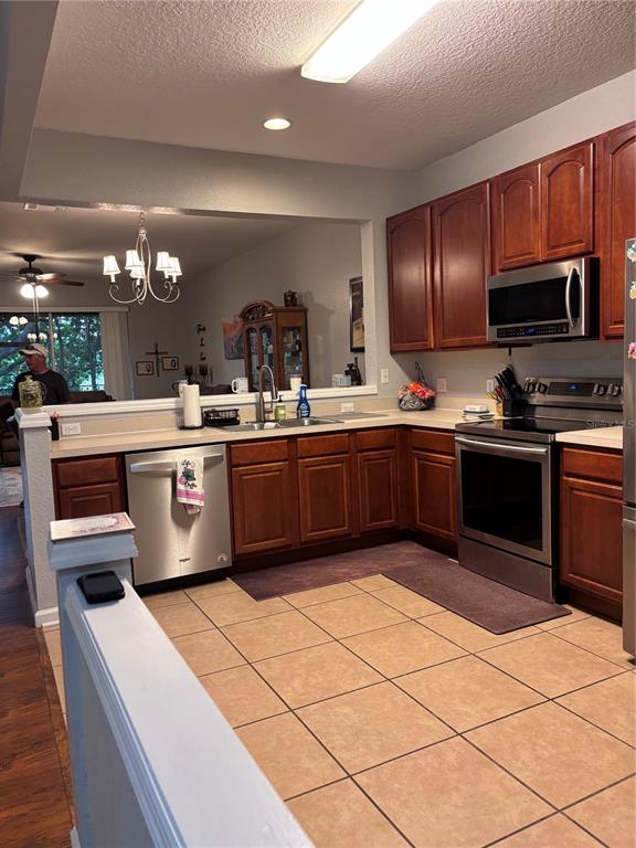 A kitchen features wood cabinets, stainless steel appliances, and tile flooring — 1121 LOYOLA COURT, SANFORD, FL