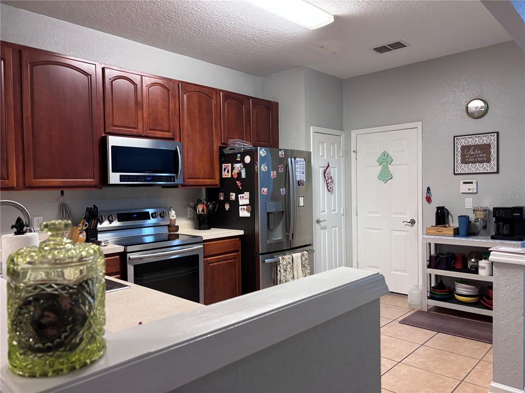 A kitchen features dark wood cabinets, stainless steel appliances, and a white breakfast bar — 1121 LOYOLA COURT, SANFORD, FL