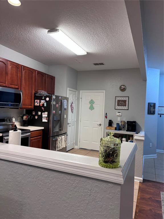 A kitchen features wood cabinets, stainless steel appliances, and a light-colored countertop — 1121 LOYOLA COURT, SANFORD, FL