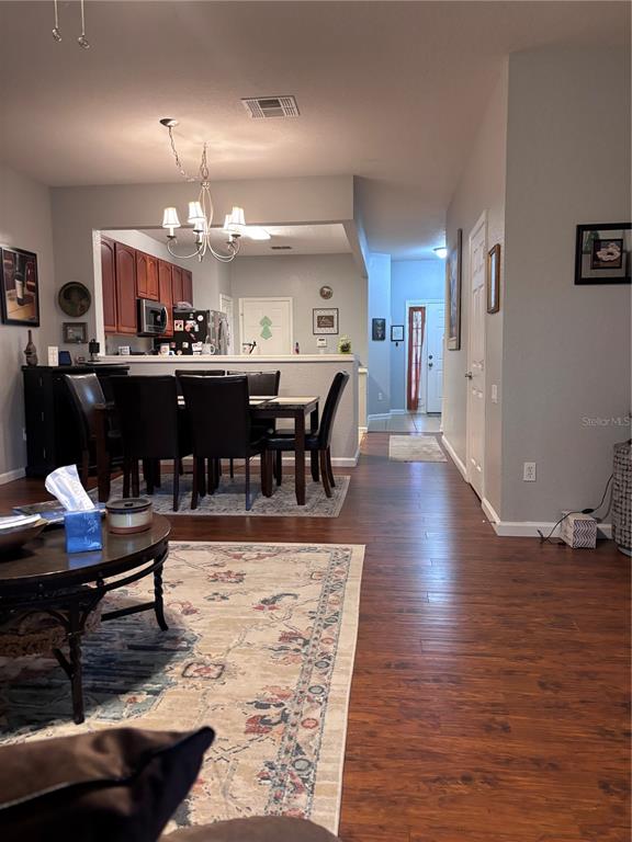 A dining area with a dark wood table and chairs sits adjacent to a kitchen — 1121 LOYOLA COURT, SANFORD, FL