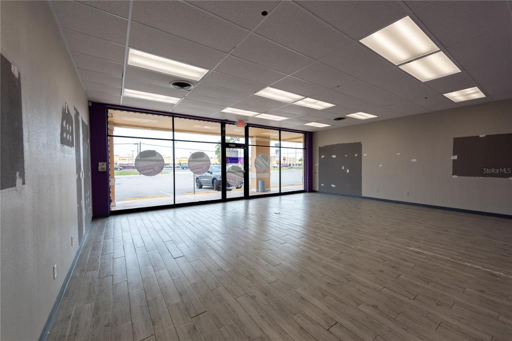 An empty commercial space features wood-look tile flooring, a drop ceiling, and large glass windows — 5118 US HWY 19, NEW PORT RICHEY, FL