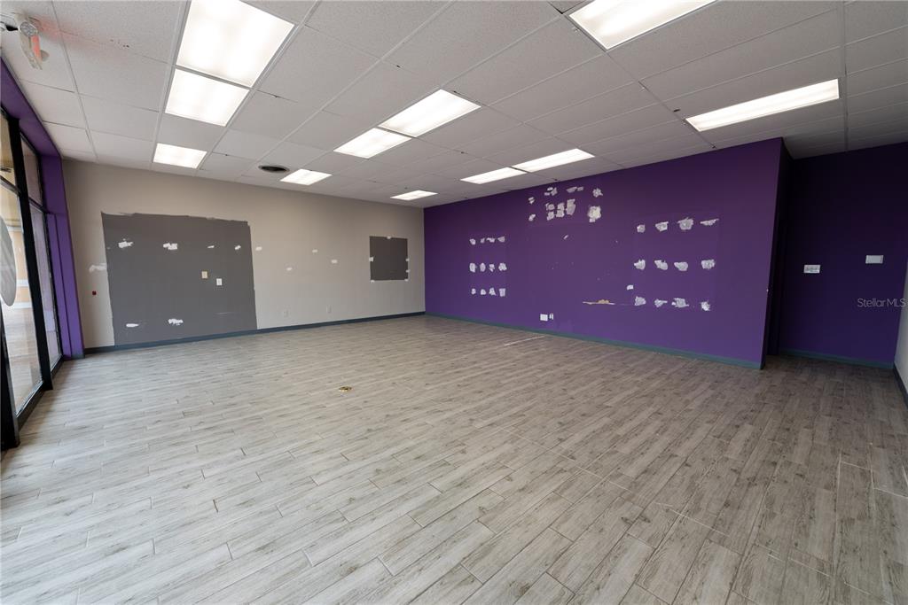 An empty commercial space features wood-look tile flooring, a drop ceiling, and purple accent walls — 5118 US HWY 19, NEW PORT RICHEY, FL