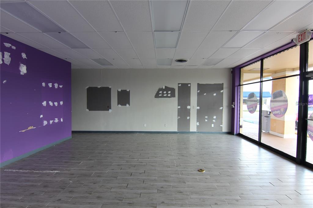 An empty commercial space features purple and gray walls, wood-look tile flooring, and glass storefront — 5118 US HWY 19, NEW PORT RICHEY, FL