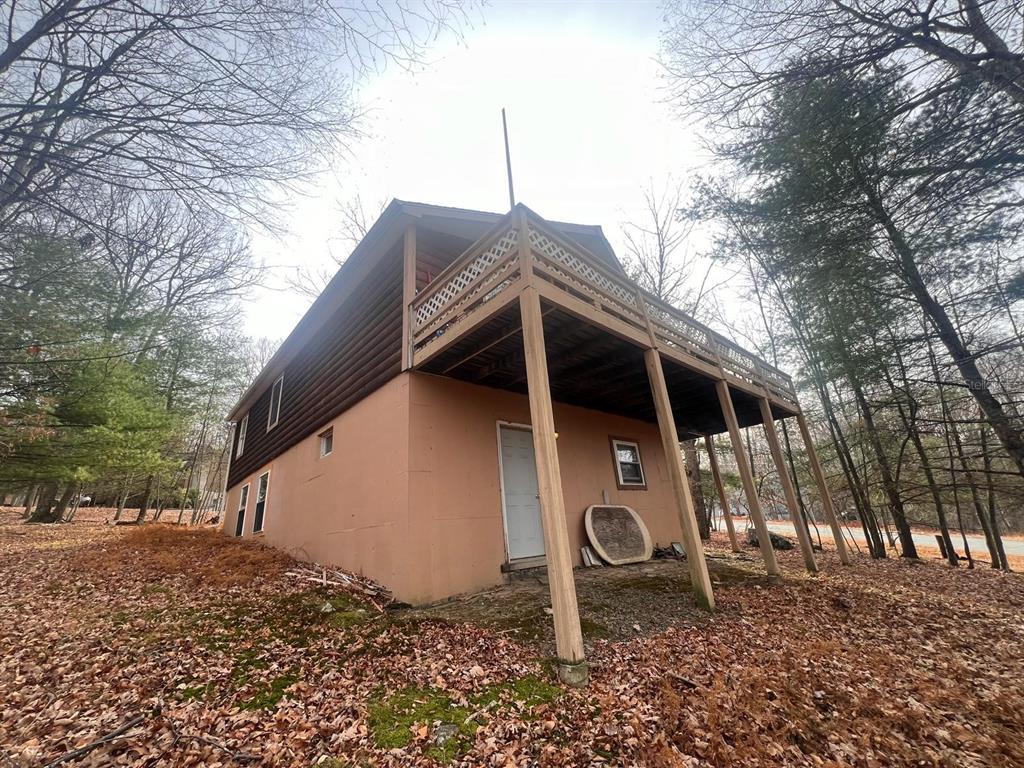 An exterior view of a two-story house with a log-sided upper level and deck — 123 ROCKY ROAD, LACKAWAXEN, PA