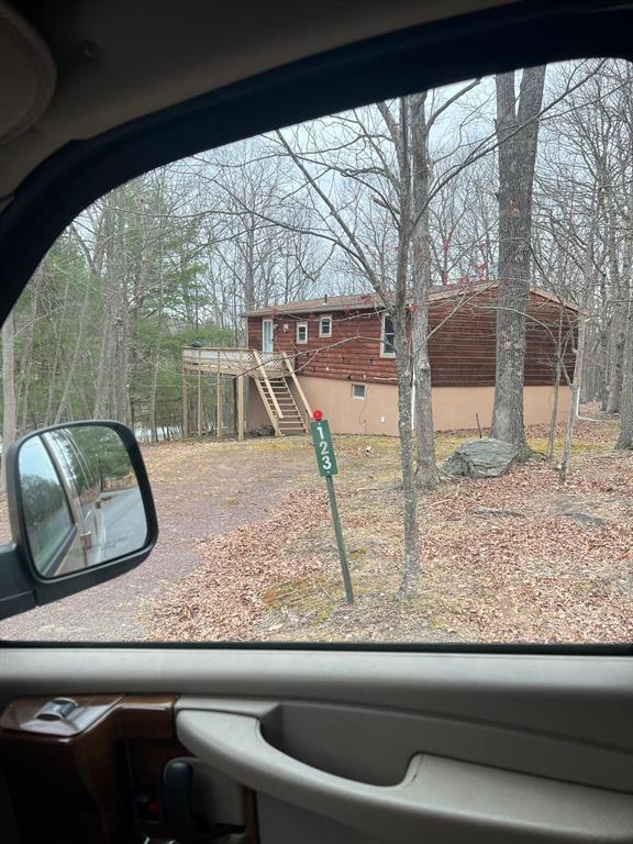 A wooden house with a raised deck and stairs sits in a wooded lot — 123 ROCKY ROAD, LACKAWAXEN, PA