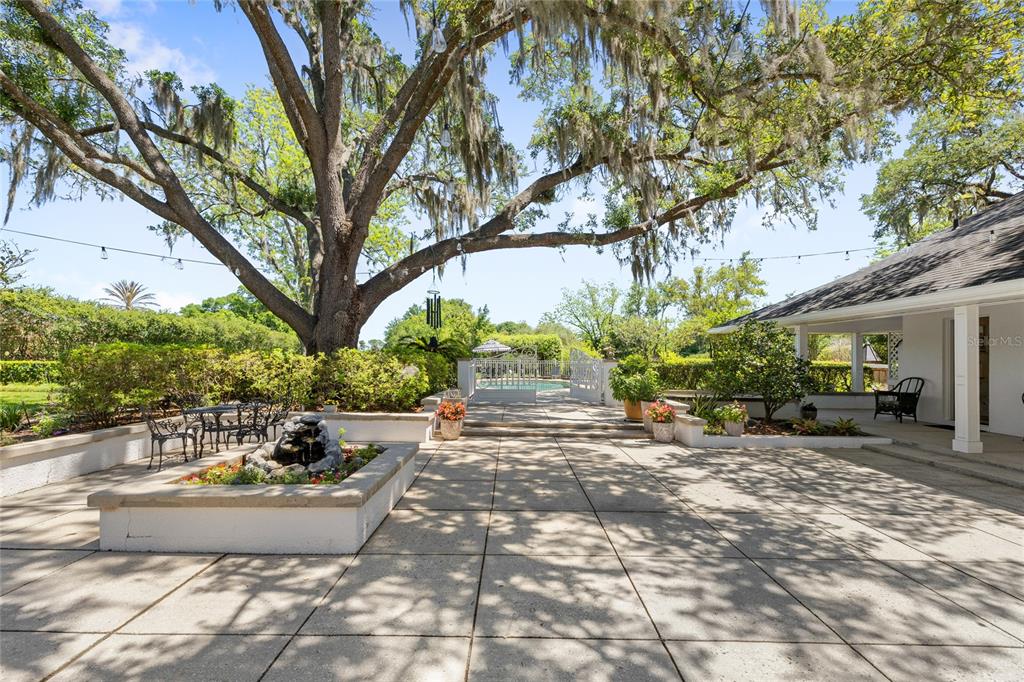 A large patio features a stone fountain, a mature oak tree, and a swimming pool — 405 SE 15TH AVENUE, OCALA, FL