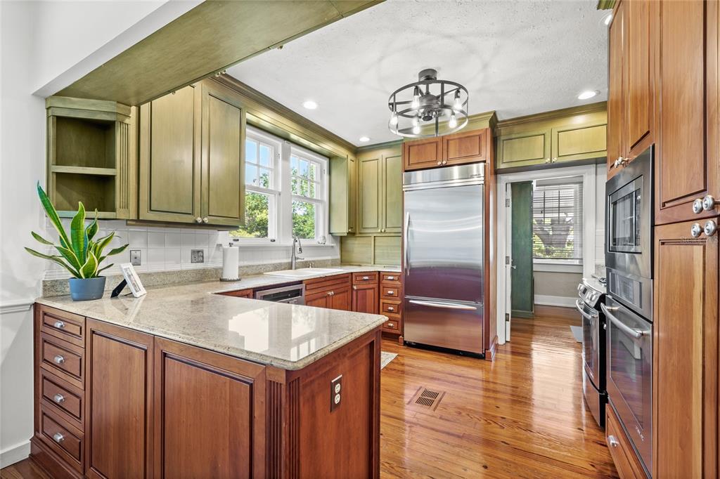 A kitchen features wood cabinets, green upper cabinets, stainless steel appliances, and granite countertops — 405 SE 15TH AVENUE, OCALA, FL