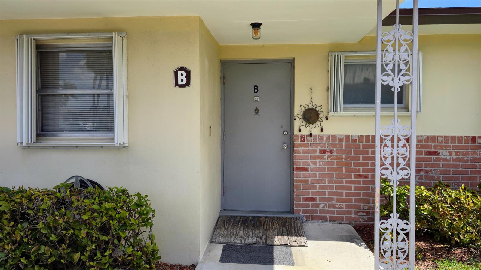 A gray front door with a wooden ramp sits between two windows on a house — 2800 Ashley Drive E # B, West Palm Beach FL 33415, WEST PALM BEACH, FL