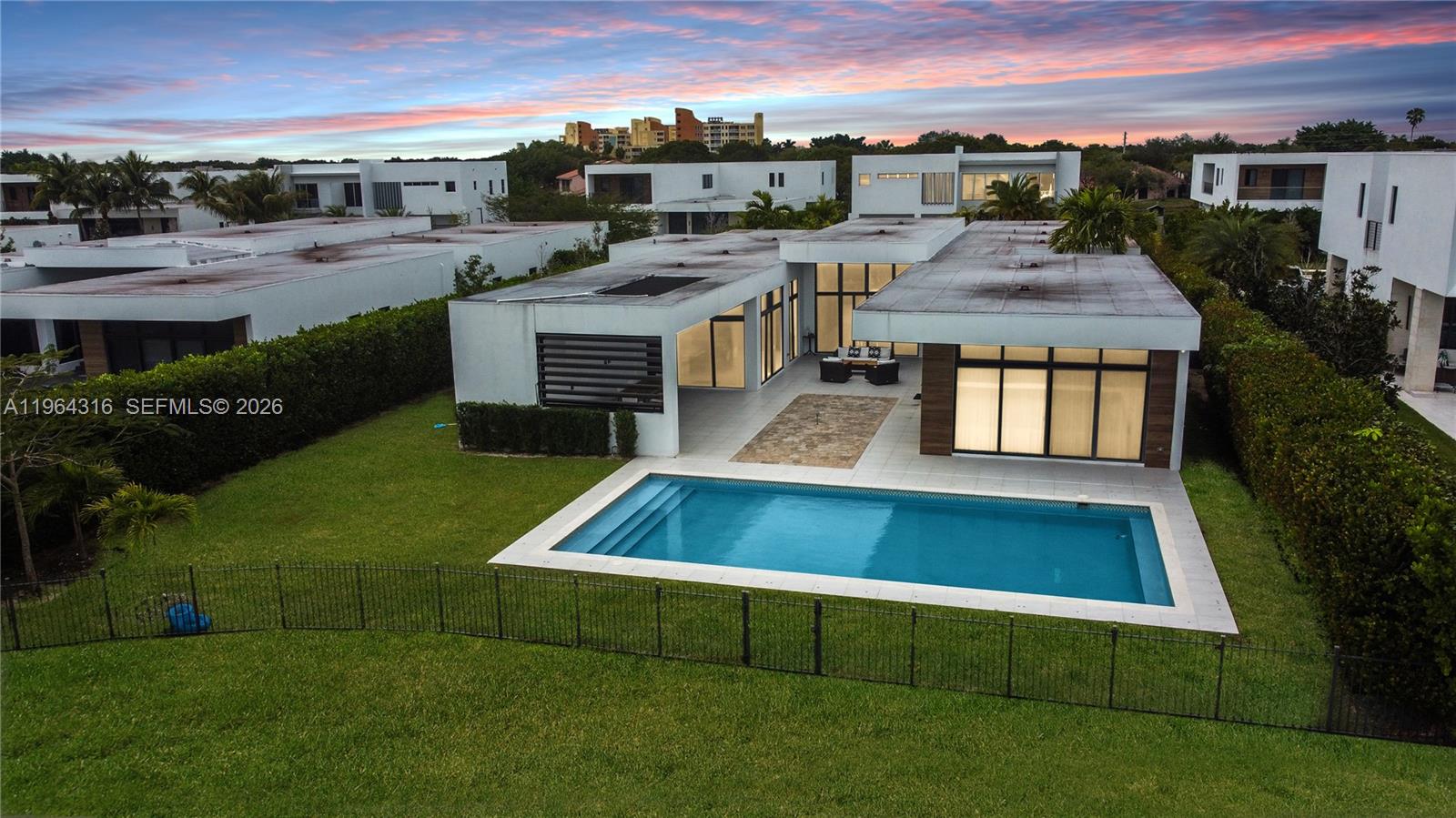An aerial view shows a modern flat-roofed house with a swimming pool and lawn — 16640 Sunset Way, Weston FL 33326, WESTON, FL
