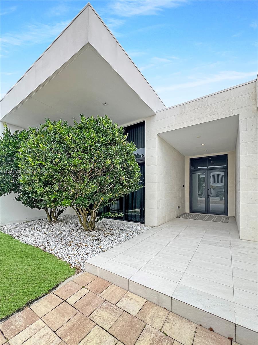 A modern house exterior features a tiled entryway, white stone walls, and a large bush — 16640 Sunset Way, Weston FL 33326, WESTON, FL