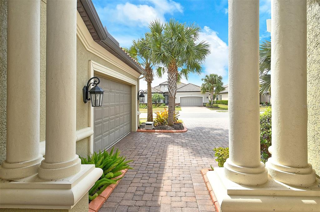 A view from a covered entryway looking out at a paved driveway and neighboring house — 4735 CABREO COURT, LAKEWOOD RANCH, FL