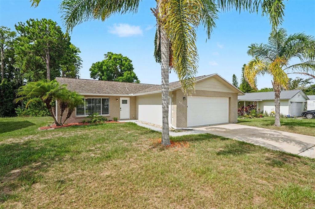 A single-story brick house with a two-car garage and palm trees in the front yard — 6822 LASSEN AVENUE, NEW PORT RICHEY, FL