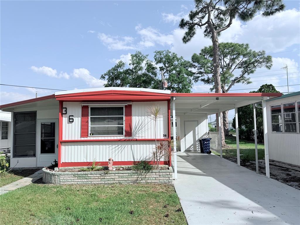 A single-story mobile home with white siding, red trim, and an attached carport — 1800 ENGLEWOOD UNIT 36, ENGLEWOOD, FL