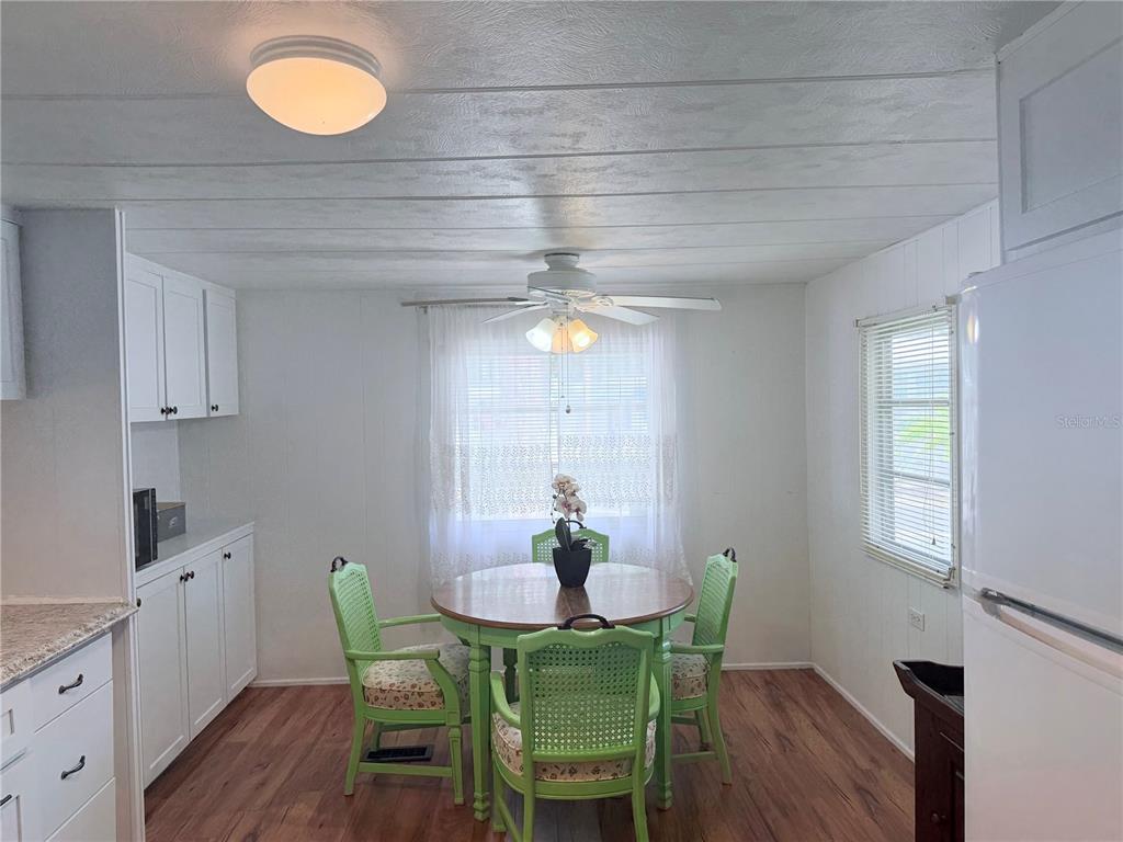 A dining area features a round wooden table with four green chairs and white cabinetry — 1800 ENGLEWOOD UNIT 36, ENGLEWOOD, FL