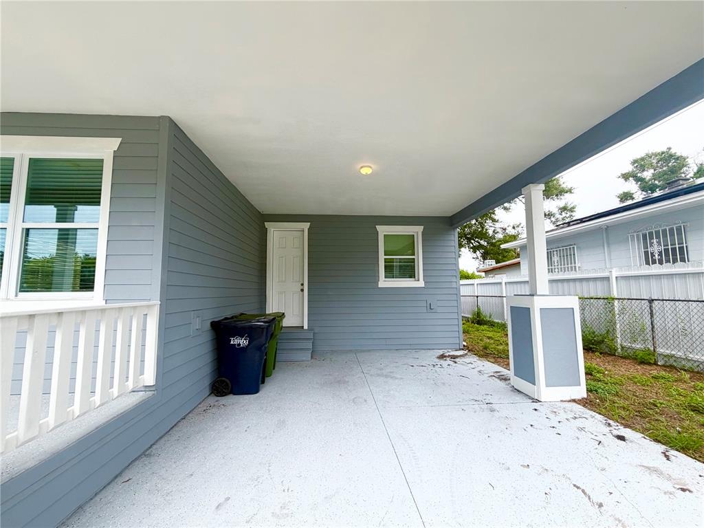 A covered concrete patio features gray siding, a white door, and a white support column — 2125 W SAINT JOSEPH STREET, TAMPA, FL