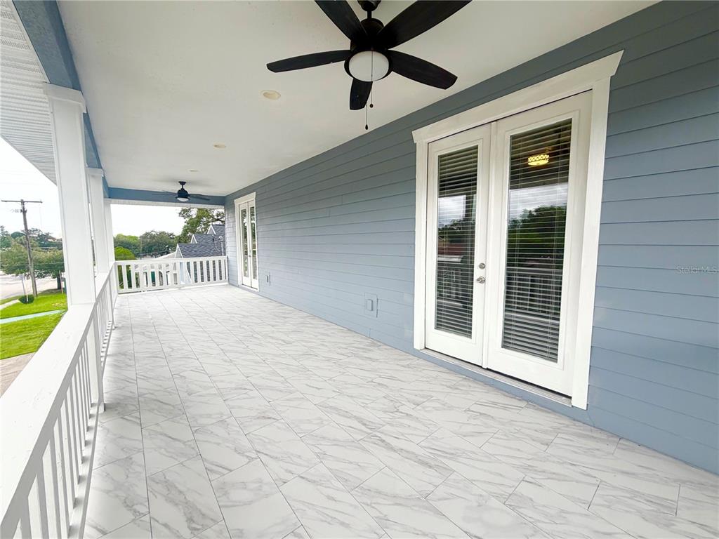 A covered porch features light blue horizontal siding, white railings, and white marble-look tile flooring — 2125 W SAINT JOSEPH STREET, TAMPA, FL
