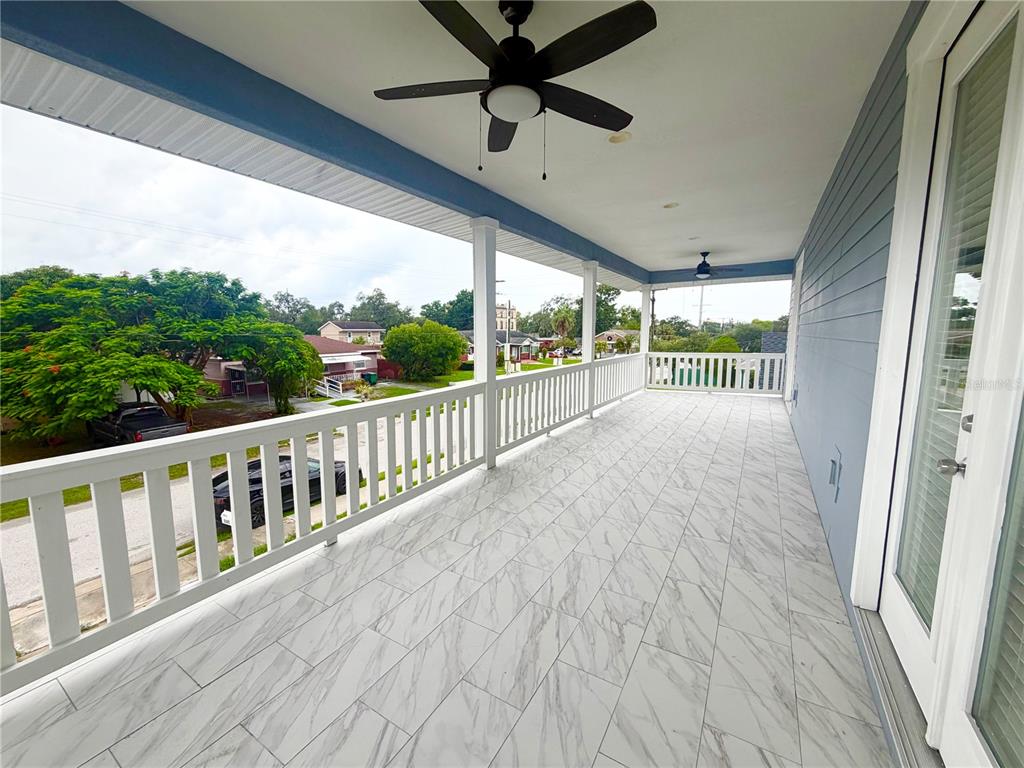 A covered balcony features white marble-look tile flooring, a white railing, and a ceiling fan — 2125 W SAINT JOSEPH STREET, TAMPA, FL