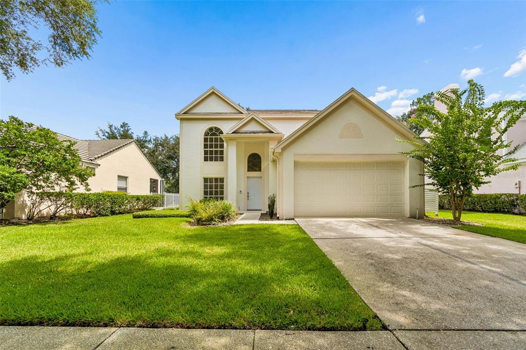 A two-story house with a beige exterior, a front-facing garage, and a green lawn — 4966 EBENSBURG DRIVE, TAMPA, FL