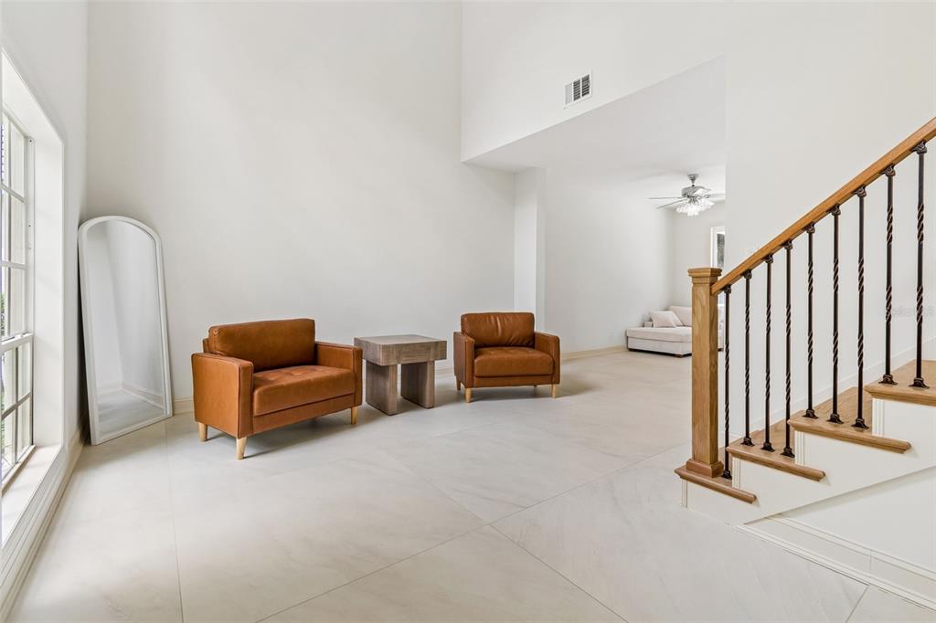 A bright living area features two leather armchairs, a side table, and a wooden staircase — 4966 EBENSBURG DRIVE, TAMPA, FL