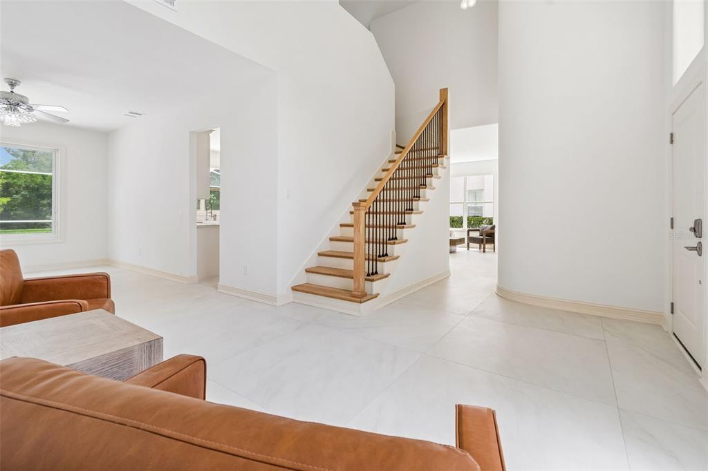 A bright entryway features white tile floors, a wooden staircase, and a view into another room — 4966 EBENSBURG DRIVE, TAMPA, FL