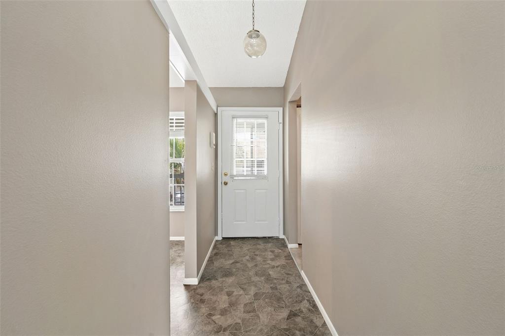 A hallway with gray walls, patterned vinyl flooring, and a white front door with blinds — 12239 SUN VISTA COURT E, TREASURE ISLAND, FL