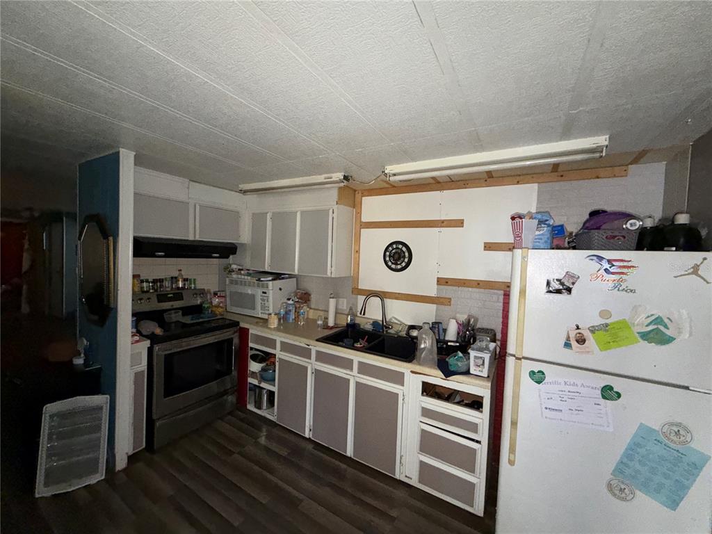A kitchen features white and grey cabinets, a stainless steel stove, and a white refrigerator — 10904 ROSS ST, TAMPA, FL