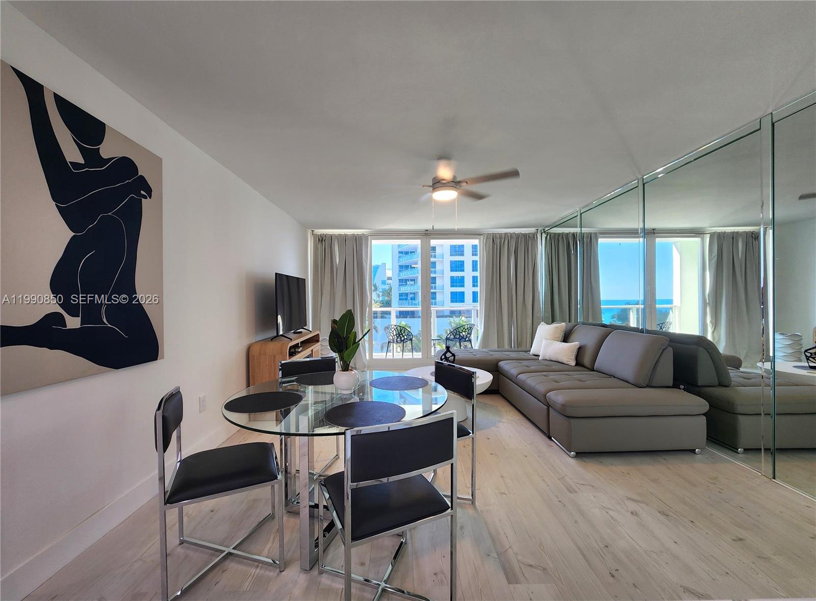 A modern living and dining area features a glass table, grey sectional, and mirrored wall — 3505 S Ocean Dr # 515, Hollywood FL 33019, HOLLYWOOD, FL