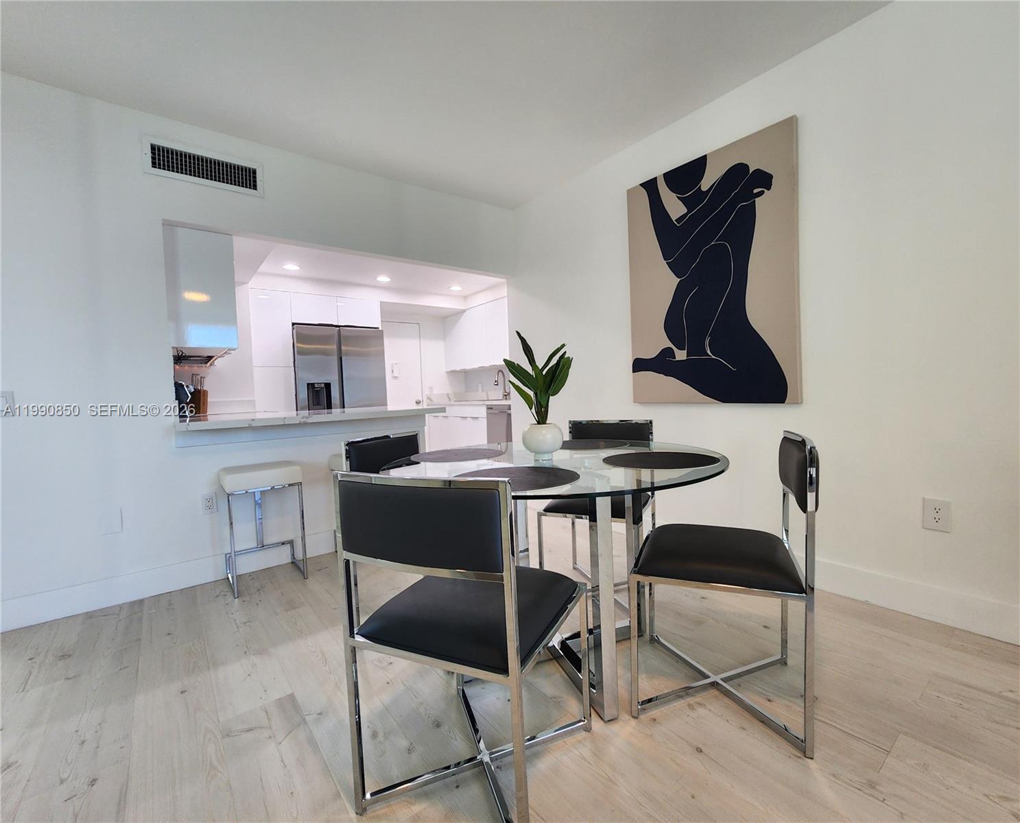 A dining area with a glass table, four black chairs, and wall art near a kitchen — 3505 S Ocean Dr # 515, Hollywood FL 33019, HOLLYWOOD, FL