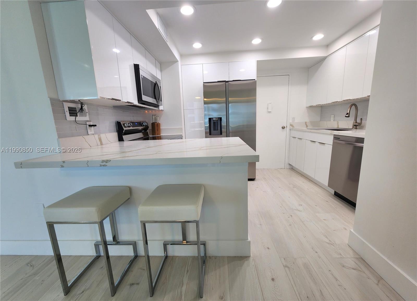 A modern kitchen features white cabinets, stainless steel appliances, and a marble-patterned breakfast bar — 3505 S Ocean Dr # 515, Hollywood FL 33019, HOLLYWOOD, FL