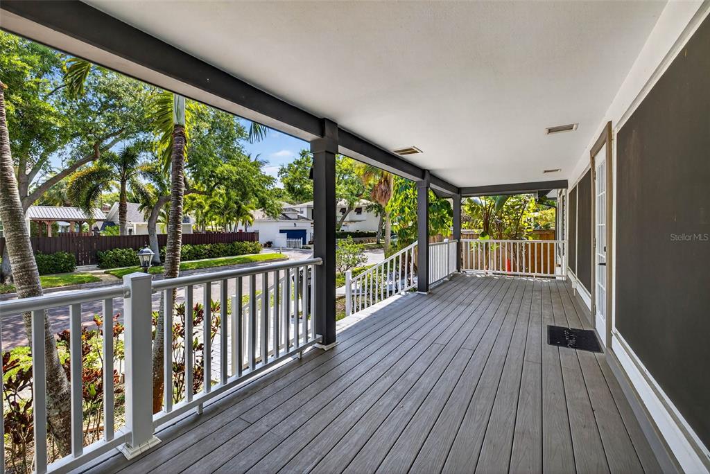 A covered porch features gray composite decking, white railings, and dark support columns — 1330 CHERRY STREET NE, ST PETERSBURG, FL