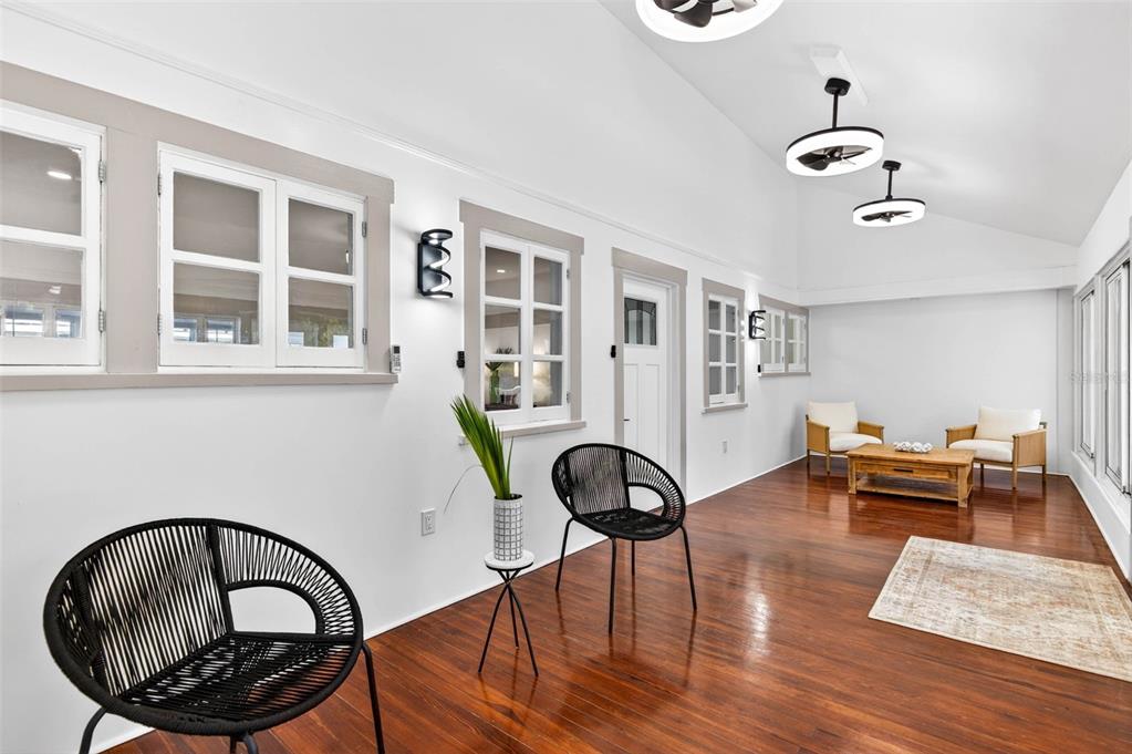 A sunroom with white walls, dark hardwood floors, black accent chairs, and modern ceiling lights — 1330 CHERRY STREET NE, ST PETERSBURG, FL