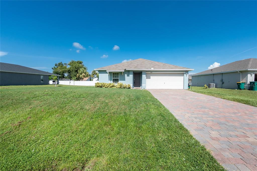 A single-story house with a light blue exterior, a paved driveway, and a grassy lawn — 1203 DESMOND STREET, PORT CHARLOTTE, FL