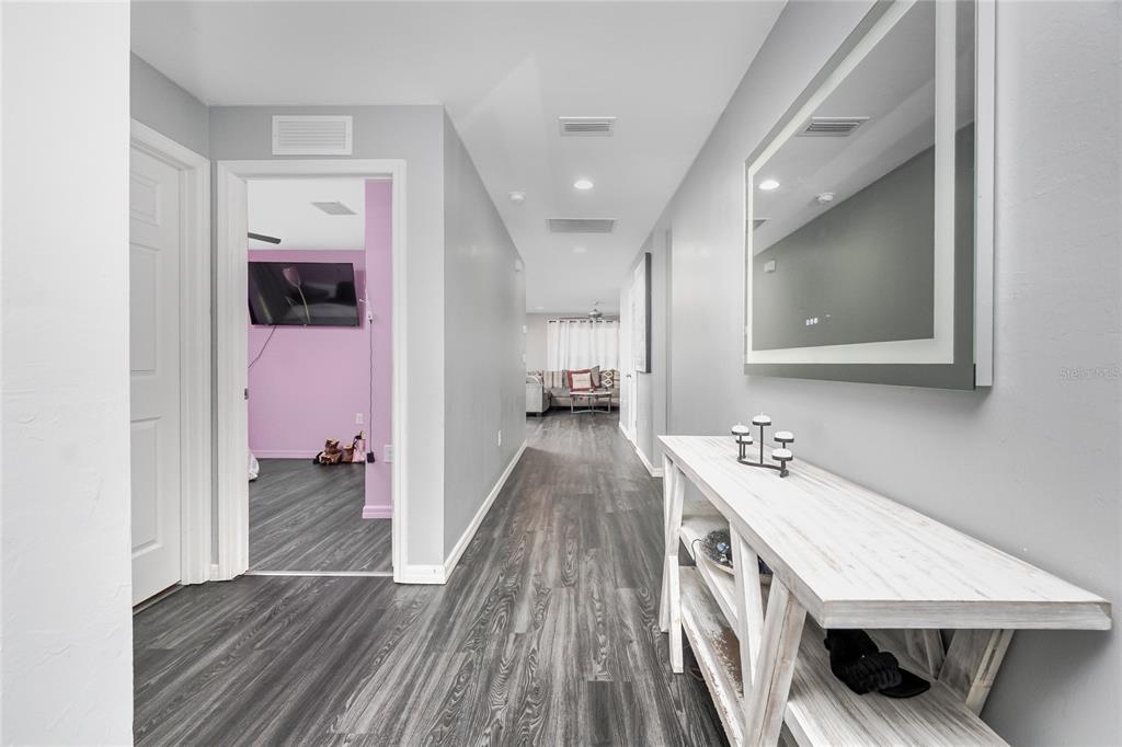 A hallway with gray wood-look flooring leads to a living area past a side room — 1203 DESMOND STREET, PORT CHARLOTTE, FL