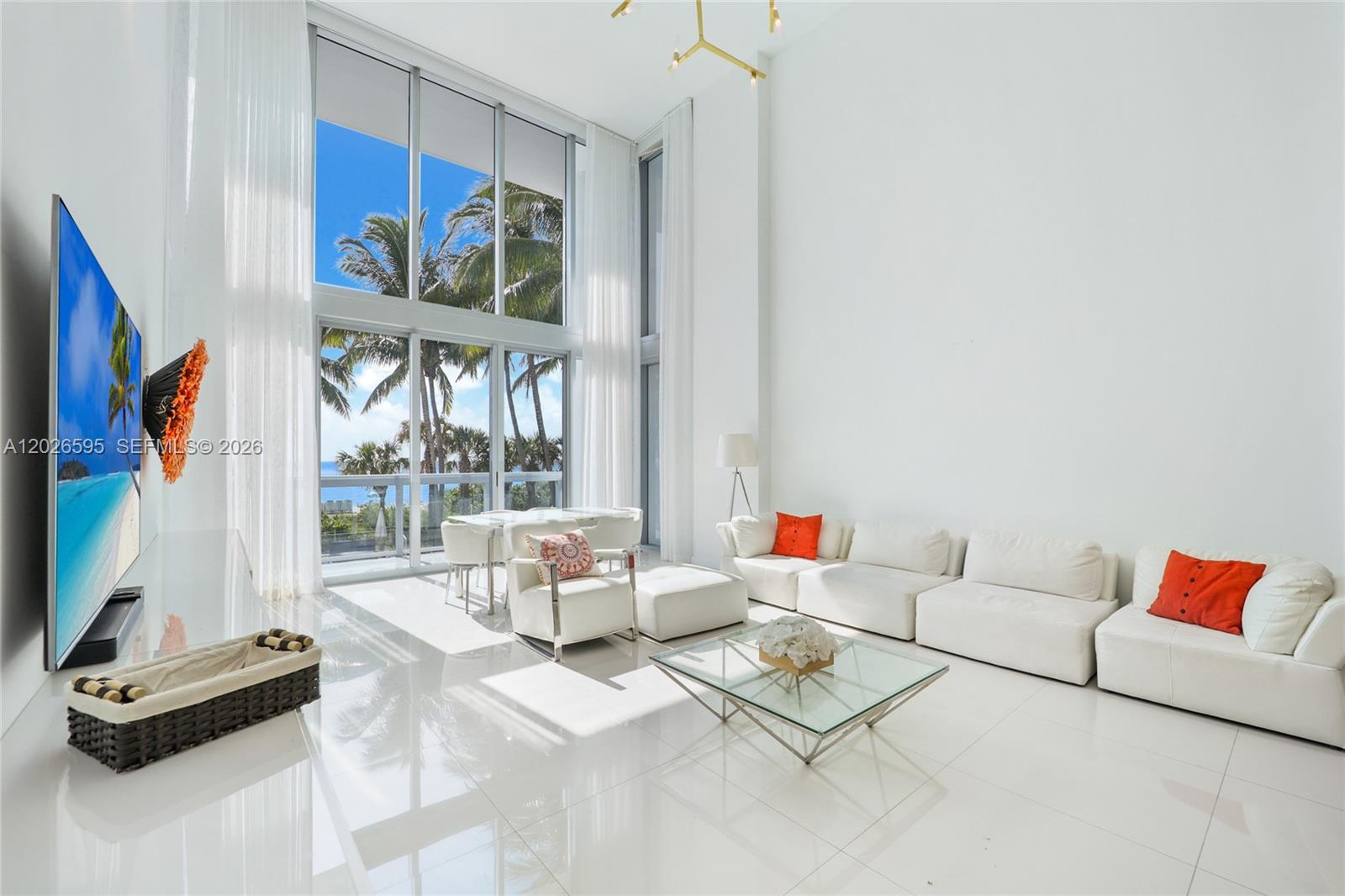 A bright, modern living room features white tile floors, a large sectional, and floor-to-ceiling windows — 6899 Collins Ave # 204, Miami Beach FL 33141, MIAMI BEACH, FL