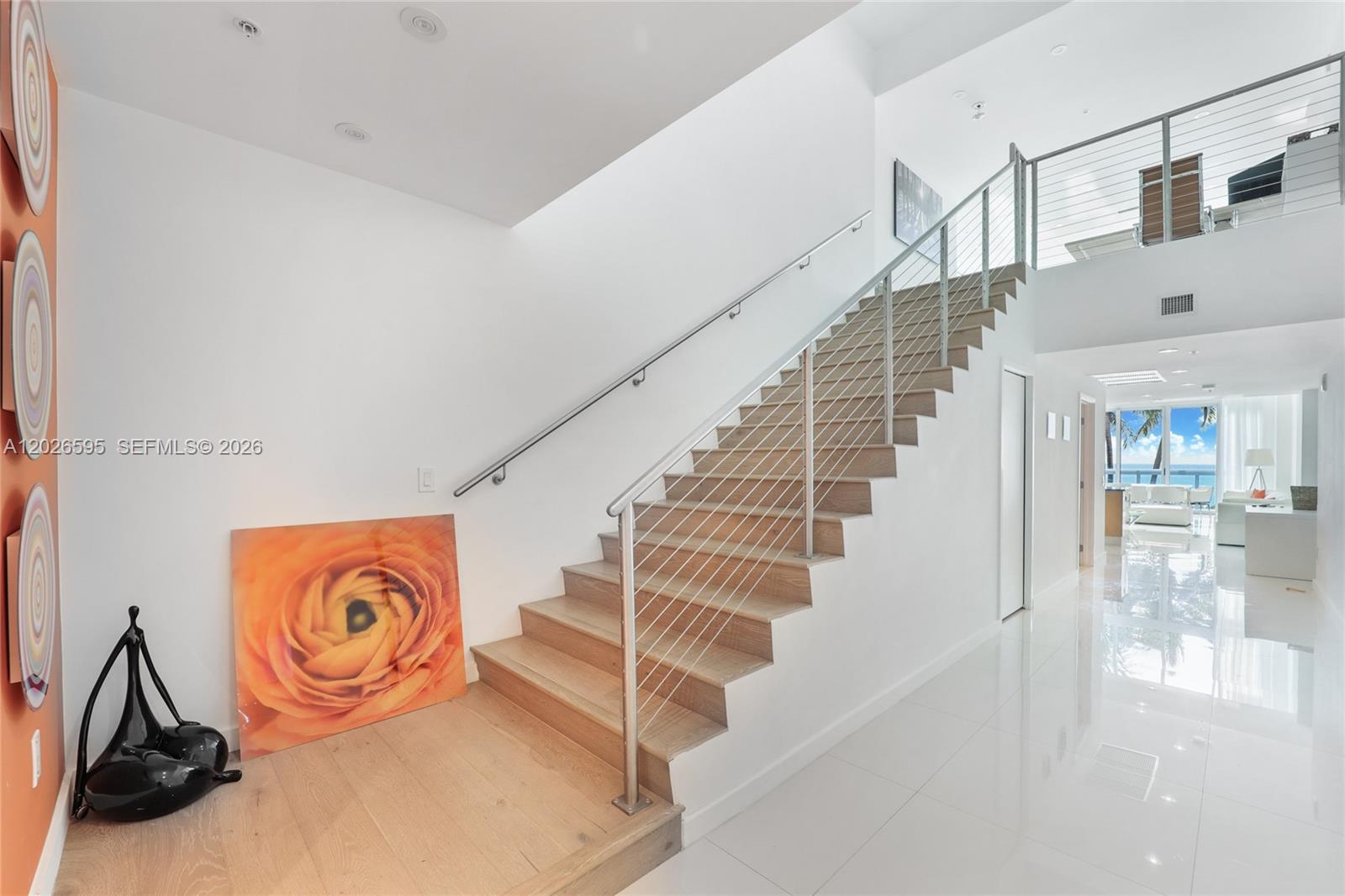 A modern staircase with light wood treads and a cable railing leads to an upper level — 6899 Collins Ave # 204, Miami Beach FL 33141, MIAMI BEACH, FL