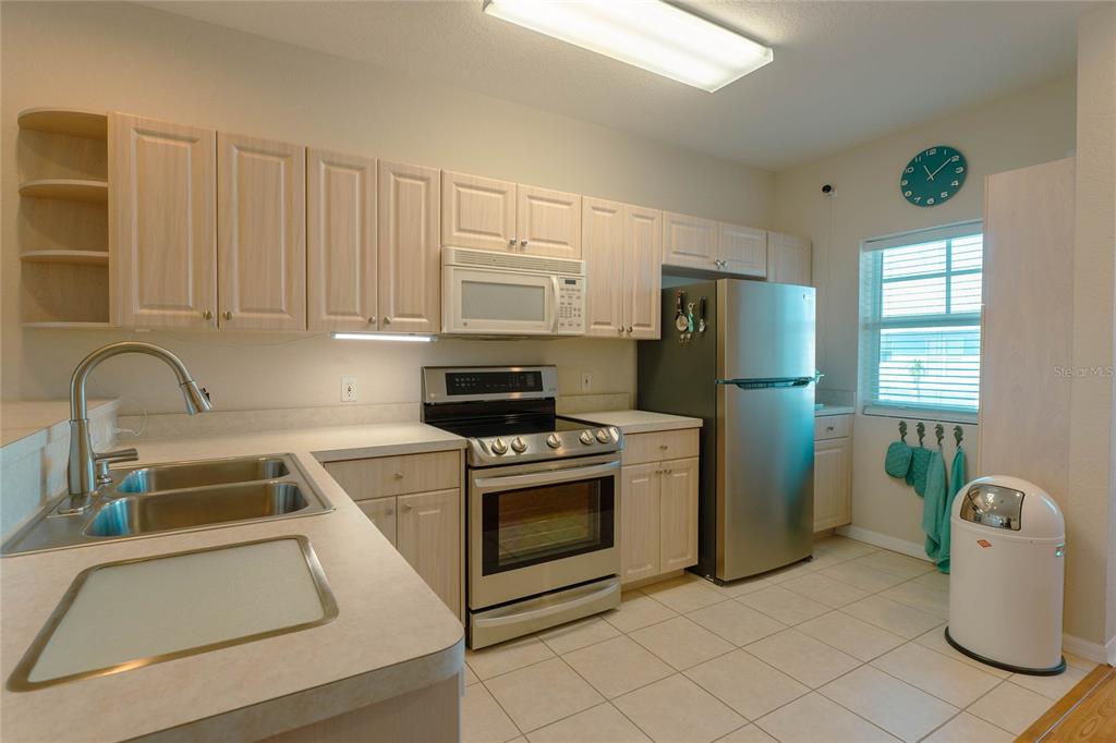 A kitchen features light wood cabinets, stainless steel appliances, and a double-basin sink — 3919 CAPE HAZE DRIVE UNIT 503, ROTONDA WEST, FL