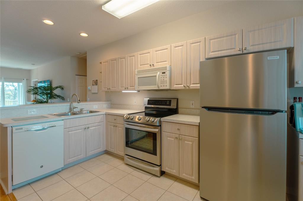 A kitchen features light wood cabinets, stainless steel appliances, and tile flooring — 3919 CAPE HAZE DRIVE UNIT 503, ROTONDA WEST, FL