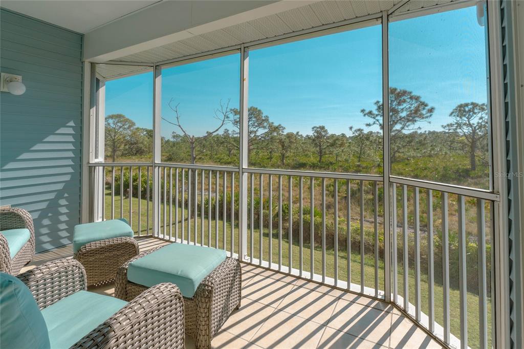 A screened-in porch with wicker furniture overlooks a grassy area and a line of trees — 3919 CAPE HAZE DRIVE UNIT 503, ROTONDA WEST, FL