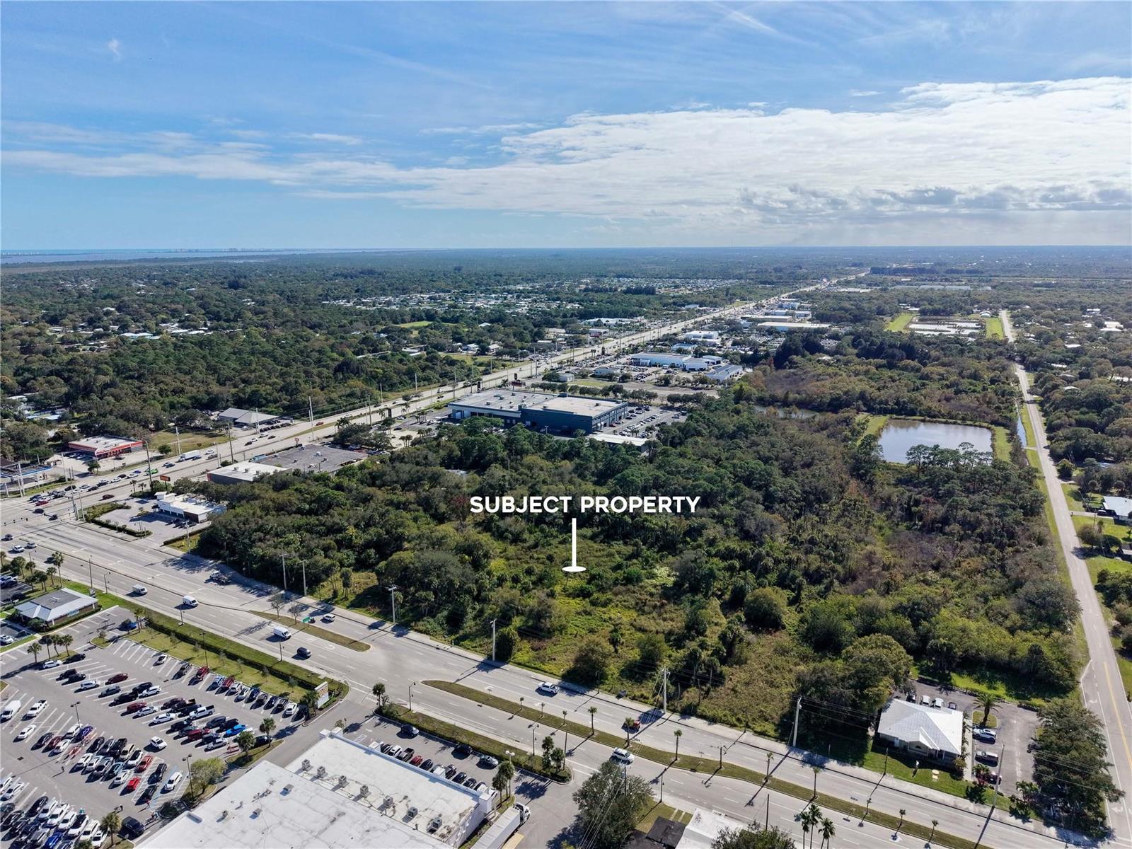 An aerial view shows a wooded, undeveloped lot situated between two busy commercial roads — 511 W Midway Road, Fort Pierce FL 34982, FORT PIERCE, FL