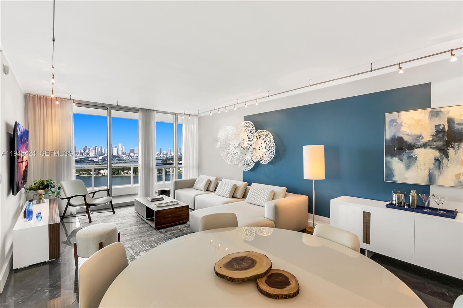A modern living room features a blue accent wall, white sectional sofa, and city views — 540 West Ave # 2311, Miami Beach FL 33139, MIAMI BEACH, FL