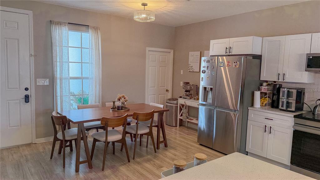 A kitchen and dining area features white cabinets, stainless steel appliances, and a wooden table — 310 SUNSET VIEW DRIVE, DAVENPORT, FL