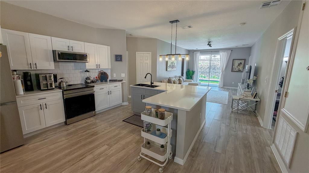 A kitchen with white cabinets, stainless steel appliances, and a central island with a cart — 310 SUNSET VIEW DRIVE, DAVENPORT, FL