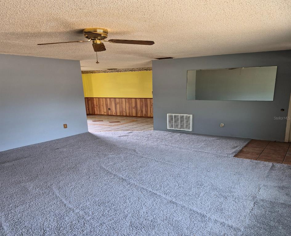 A living room features gray carpet, blue walls, a ceiling fan, and a wall mirror — 324 FORT COLLINS COURT, OCOEE, FL