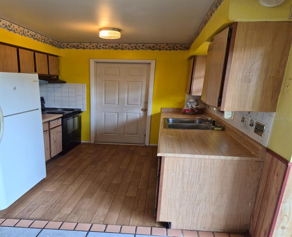 A kitchen features yellow walls, wood cabinets, laminate countertops, and wood-look flooring — 324 FORT COLLINS COURT, OCOEE, FL