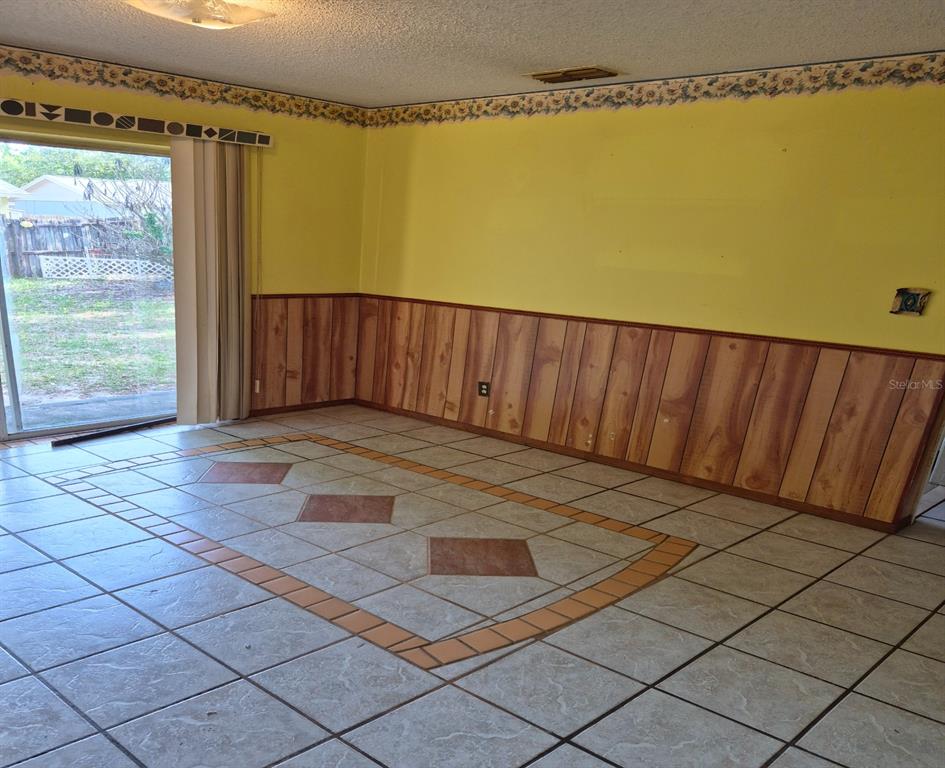 A room with yellow walls, wood paneling, tiled flooring, and a sliding glass door — 324 FORT COLLINS COURT, OCOEE, FL
